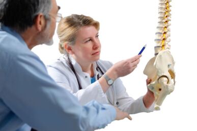 Mjeku konsulton pacientin për shenjat e osteokondrozës së shpinës torakale